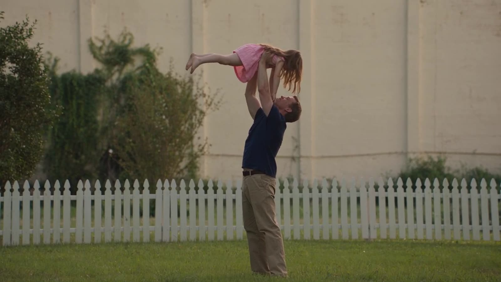 A father playing with his daughter in a backyard