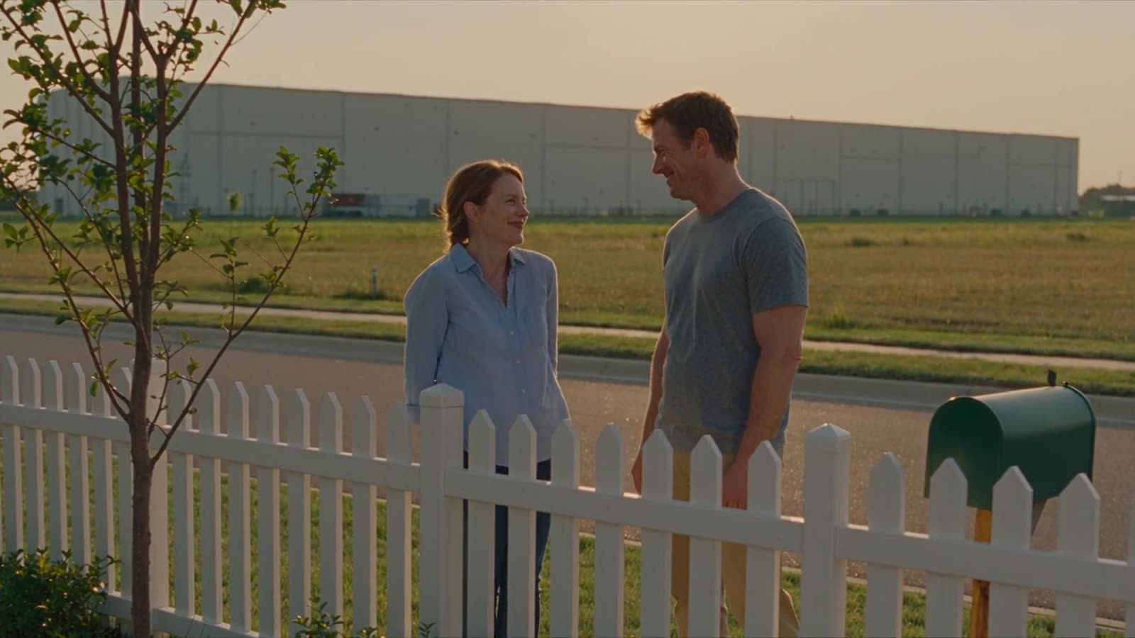 Neighbors talking by a fence near a plant